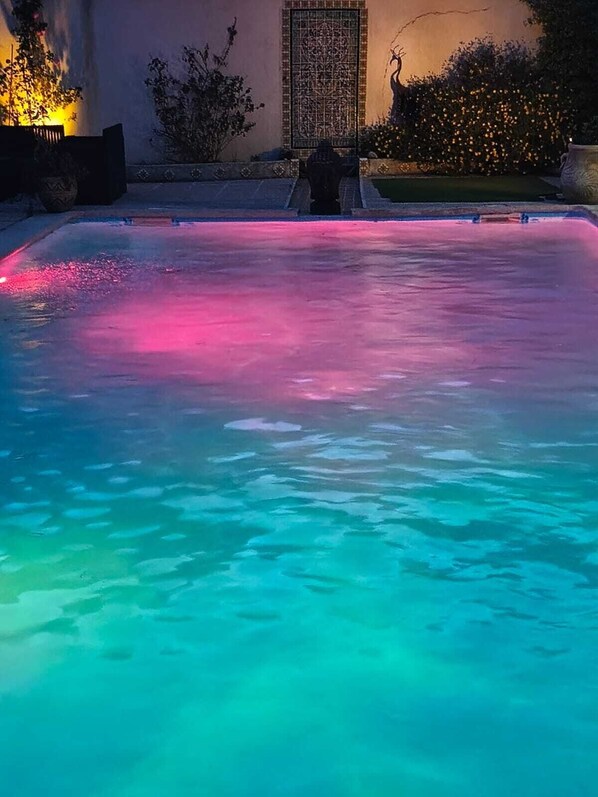 A swimming pool with a clear water surface and a decorative tile wall in the background.