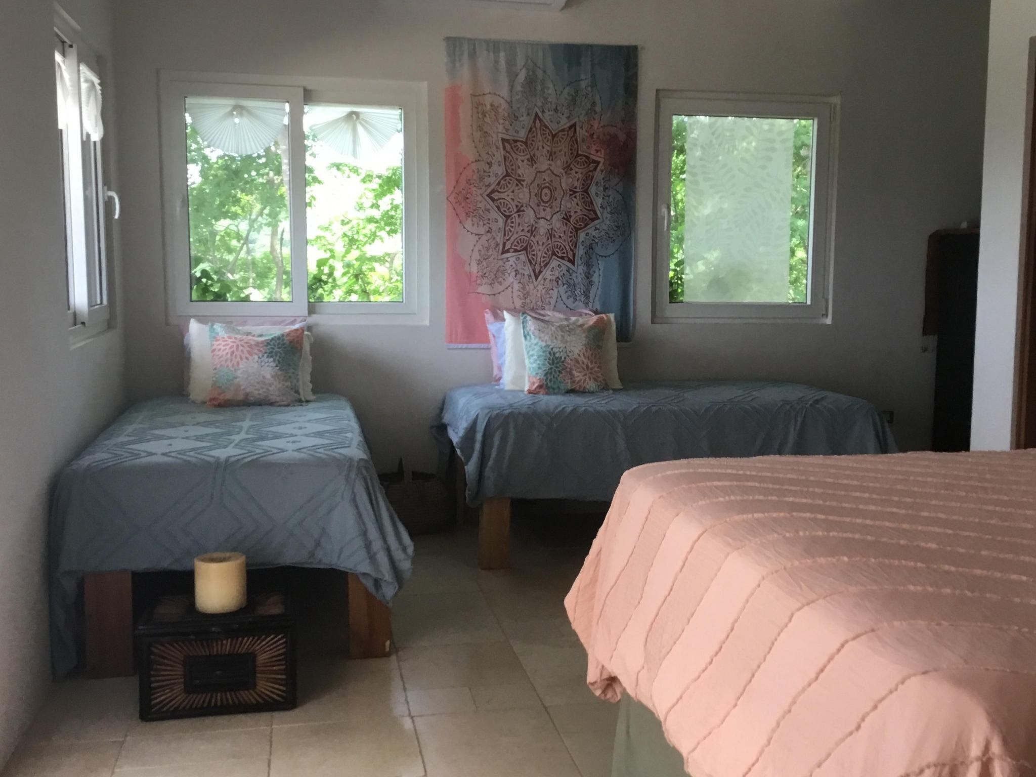 Un dormitorio con dos camas, una ventana y un tapiz.