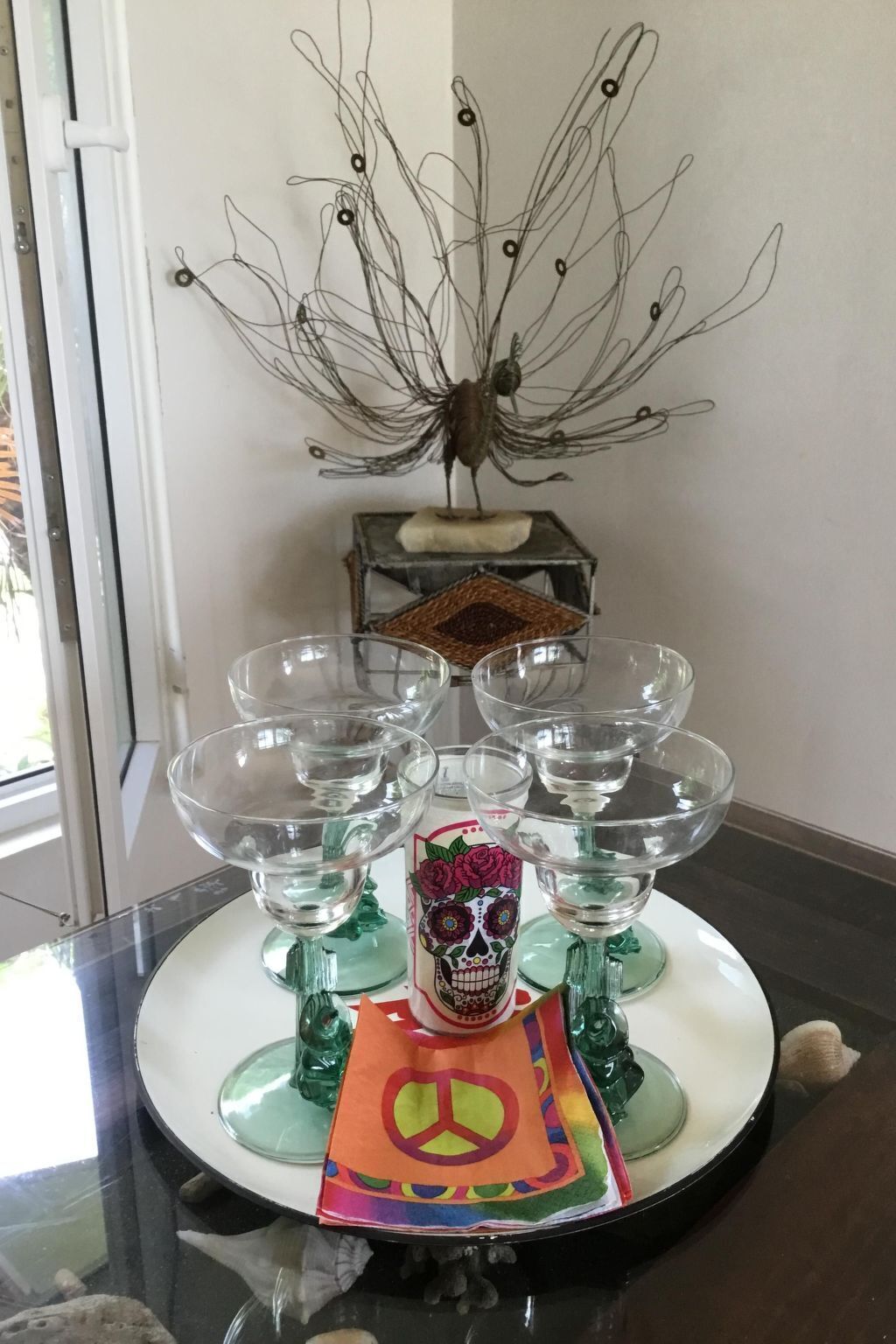 Un tavolo con una scultura in metallo a forma di uccello decorativo, un cesto di vimini e un sottopiatti con un simbolo della pace colorato.