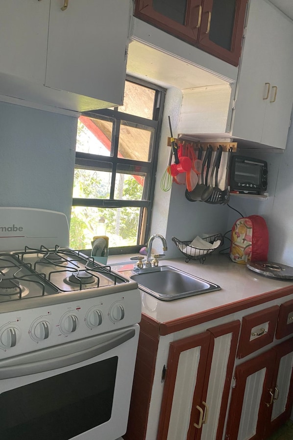 A compact kitchen with a gas stove, a sink, and a window.