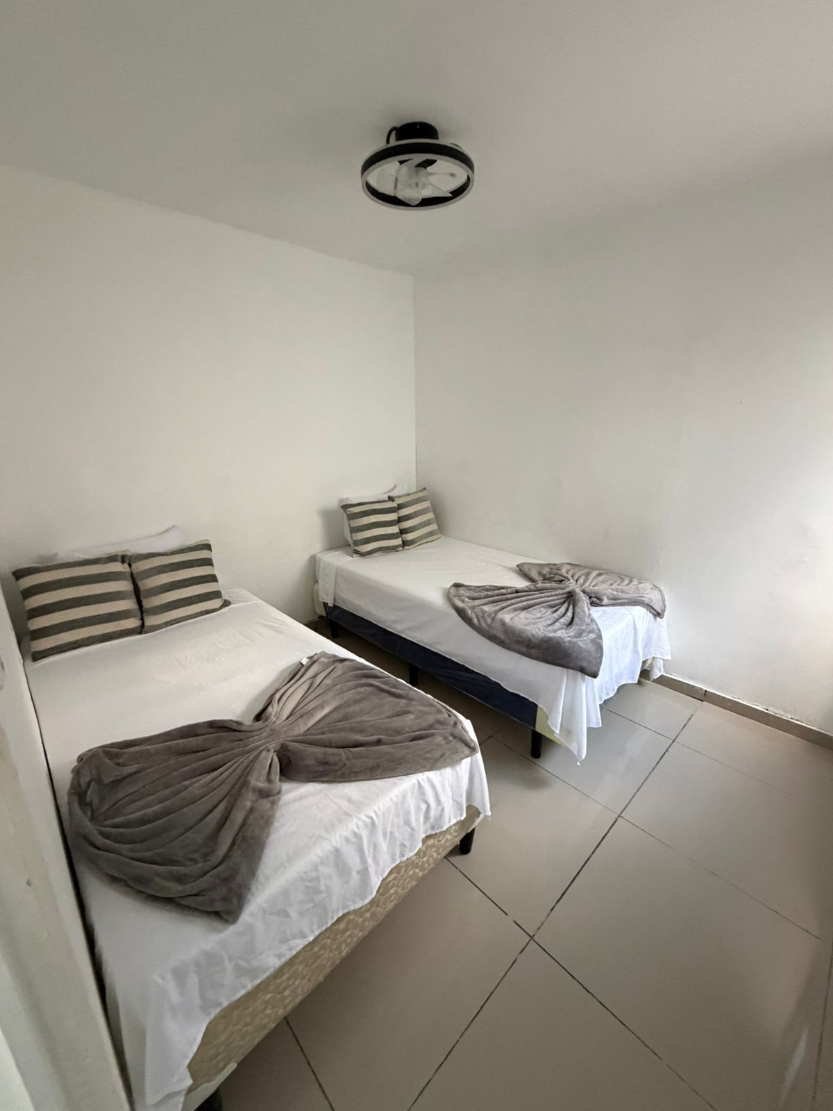 A room with two single beds, each with a striped pillow and a blanket.