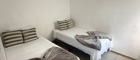 A room with two single beds, each with a striped pillow and a blanket.