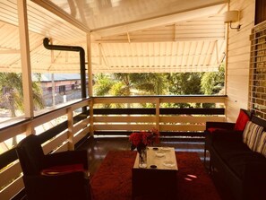 A sunlit balcony with a wooden railing, a small table with a vase, and a sofa with cushions. - Sulda's Home, eine Oase im Südwesten von Paramaribo by Interhome (Paramaribo)