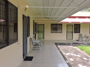 A covered outdoor area with a tiled floor, a few chairs, and a small table.