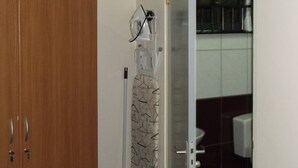 Un baño con un mueble de madera, zona de ducha y un inodoro.