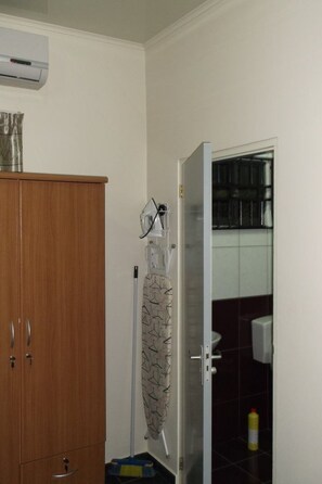 A bathroom with a wooden cabinet, a shower area, and a toilet.