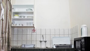 Cocina compacta con microondas, estufa y señal de no fumar.