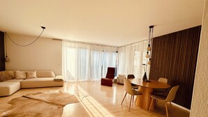 Ett modernt vardagsrum med en soffa, ett matbord och stolar. Det ligger en stor matta på golvet.