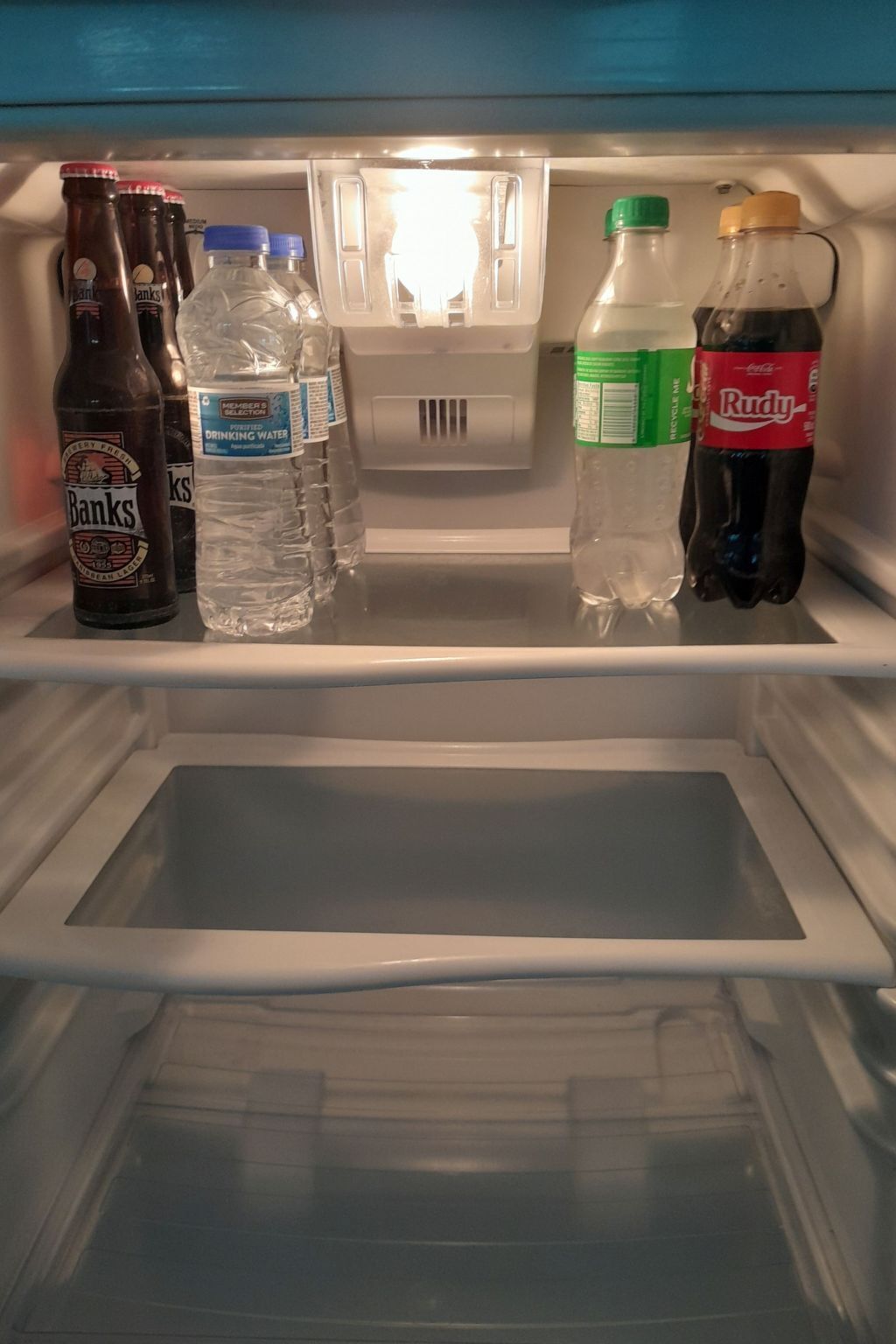 Ein offener Kühlschrank mit Regalen, auf denen Wasser-, Soda- und Bierflaschen stehen.