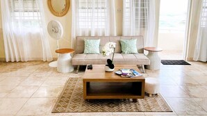 A living room with a beige sofa, two side tables, a coffee table, and a patterned rug. - Gelassenes "Island Escape" mit Meerblick by Interhome (Christ Church)