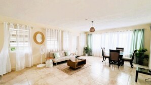 A spacious living room with a sofa, coffee table, and dining area. - Gelassenes "Island Escape" mit Meerblick by Interhome (Christ Church)