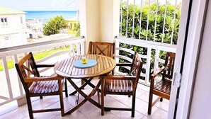 A balcony with a round wooden table and four chairs, a view of the sea, and a white railing. - "Island Getaway Apt" mit Meerblick by Interhome (Christ Church)