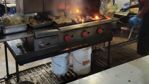A commercial kitchen with a grill, cooking utensils, and a worker. - "Island Getaway Apt" mit Meerblick by Interhome (Christ Church)