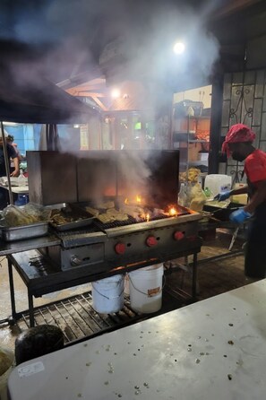 Een professionele keuken met een grill, kookgerei en een medewerker.