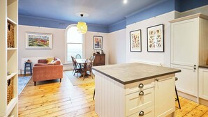 A modern kitchen with wooden flooring, a dining area with a table and chairs, and a living room with a sofa and a coffee table. - Host and Stay | Balmoral Terrace (Saltburn-by-the-Sea)