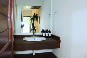 Une salle de bain avec un lavabo blanc, un plan de toilette marron foncé et un miroir au-dessus.