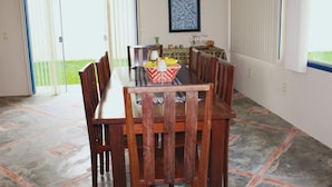 A dining area with a table and chairs, a framed picture on the wall, and a view through the sliding glass door. - Casa ampla com jardim e 3 suítes em Novo Airão (Novo Airão)