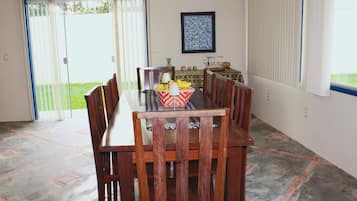 Uma área de refeições com mesa e cadeiras, um quadro na parede e vista pela porta de vidro deslizante.