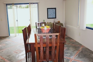 A dining area with a table and chairs, a framed picture on the wall, and a view through the sliding glass door. - Casa ampla com jardim e 3 suítes em Novo Airão (Novo Airão)