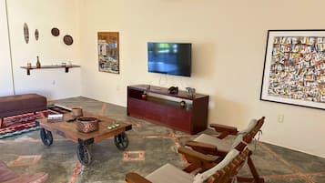Uma sala de estar com televisão, mobiliário de madeira, um sofá e objetos decorativos.