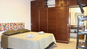 A bedroom with a bed, a wardrobe, a bathroom, and a colorful abstract painting on the wall. - Casa ampla com jardim e 3 suítes em Novo Airão (Novo Airão)