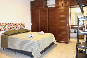 Une chambre à coucher comprenant un lit, une armoire, une salle de bain et un tableau abstrait aux couleurs vives accroché au mur.