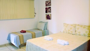 A hotel room with two beds, a window with blinds, and three framed pictures on the wall. - Casa ampla com jardim e 3 suítes em Novo Airão (Novo Airão)