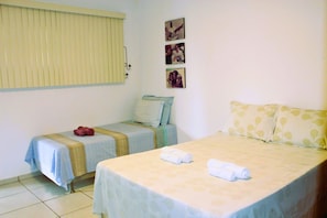 A hotel room with two beds, a window with blinds, and three framed pictures on the wall. - Casa ampla com jardim e 3 suítes em Novo Airão (Novo Airão)