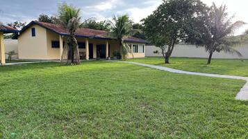 A building with a red-tiled roof, a covered porch, and a well-maintained lawn.