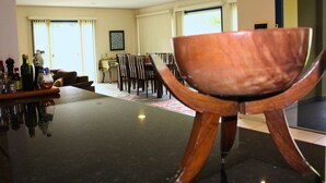 A dining area with a table and chairs, a bar with bottles, and a large window with curtains. - Casa ampla com jardim e 3 suítes em Novo Airão (Novo Airão)