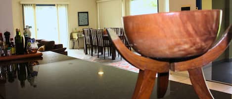 A dining area with a table and chairs, a bar with bottles, and a large window with curtains.