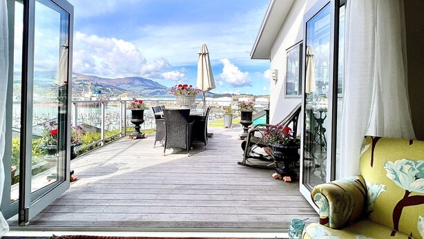 Un balcon doté d’une terrasse en bois, de mobilier d’extérieur et de plantes en pot.