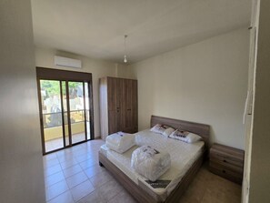 Ein Schlafzimmer mit Bett, Kleiderschrank und einer Glastür zum Außenbereich.