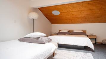 Ein Schlafzimmer mit zwei Betten, einer Holzbalkendecke und einer weißen Stehlampe.