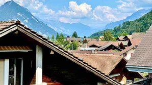 Ein dörfliches Bergidyll mit traditionellen Häusern und wolkenlosem Himmel.