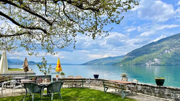 Eine Terrassensitzgelegenheit am Seeufer mit Blick auf See und Berge.