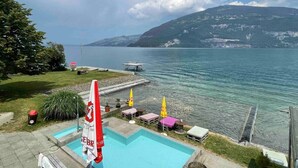 Ein Schwimmbecken mit Blick auf einen See und Berge im Hintergrund.