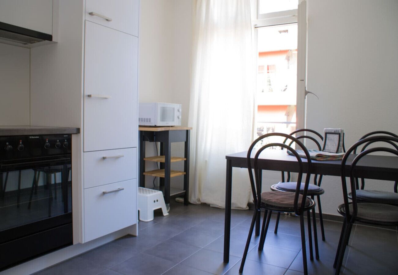 A kitchen with white cabinets, a black stove, and a dining area with a table and chairs.