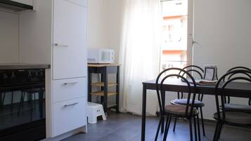 A kitchen with white cabinets, a black stove, and a dining area with a table and chairs.