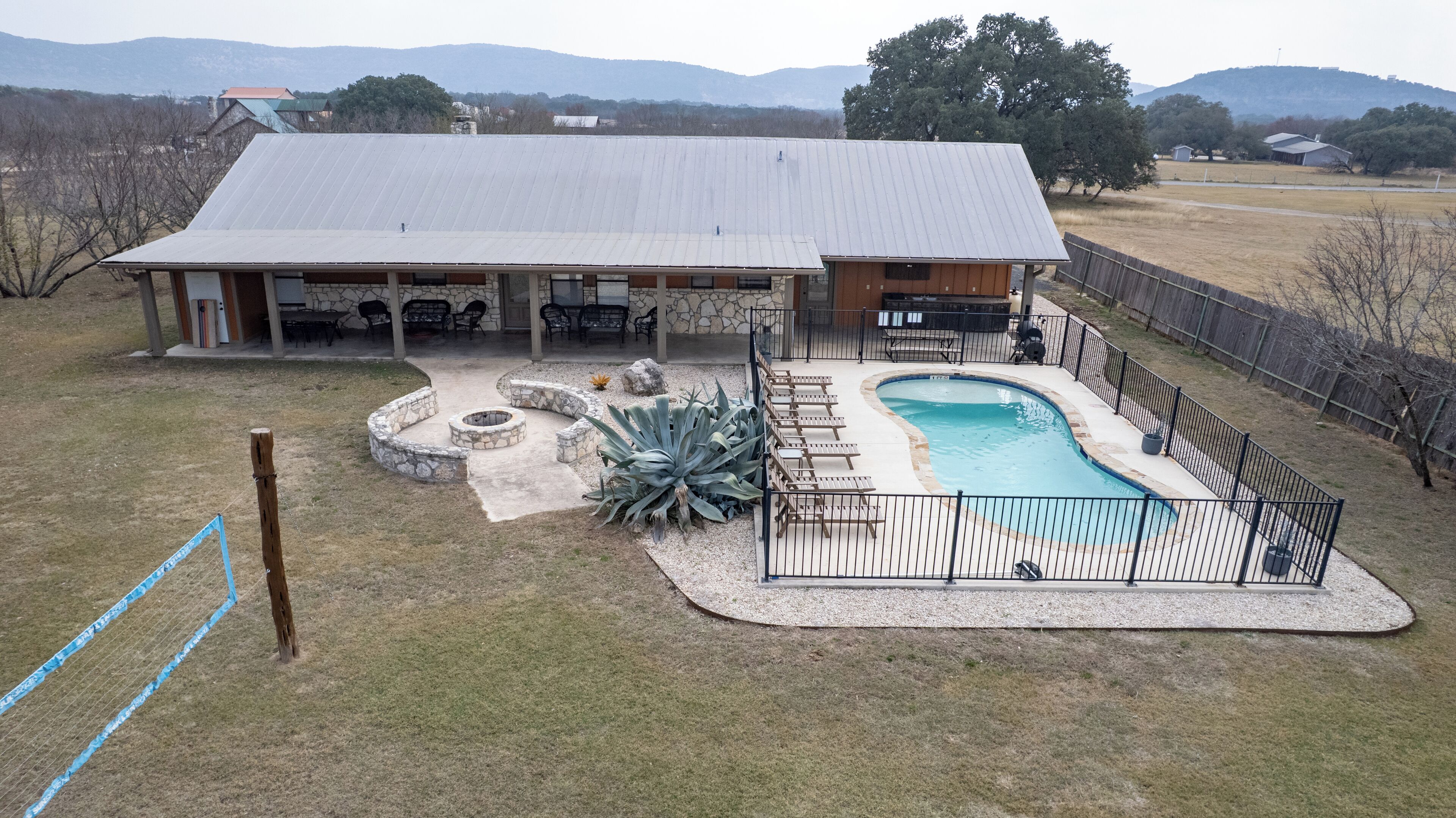 A residential property with a swimming pool, patio area, and stone fire pit.