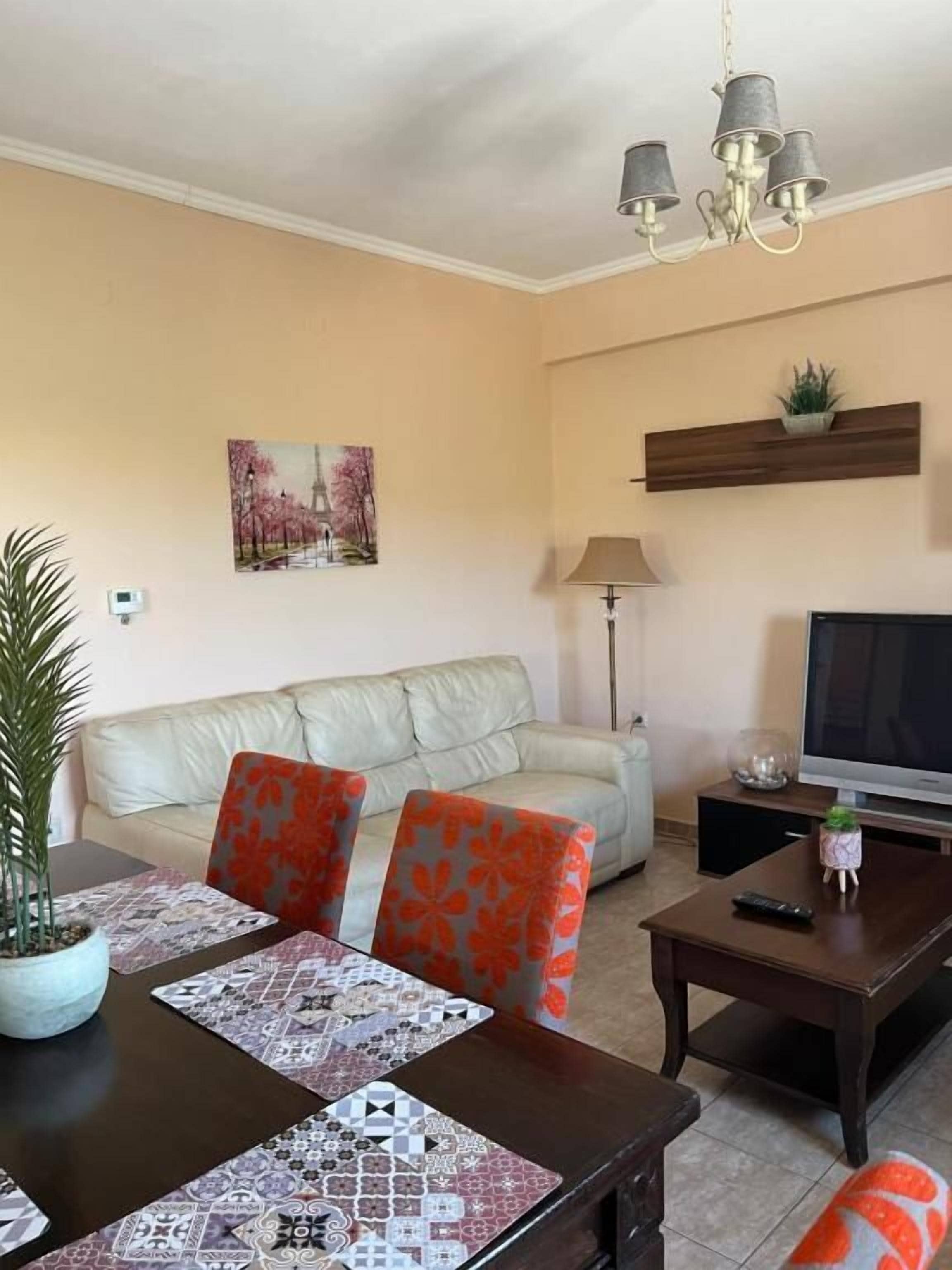 A living room with a sofa, a coffee table, a TV, and a painting on the wall.