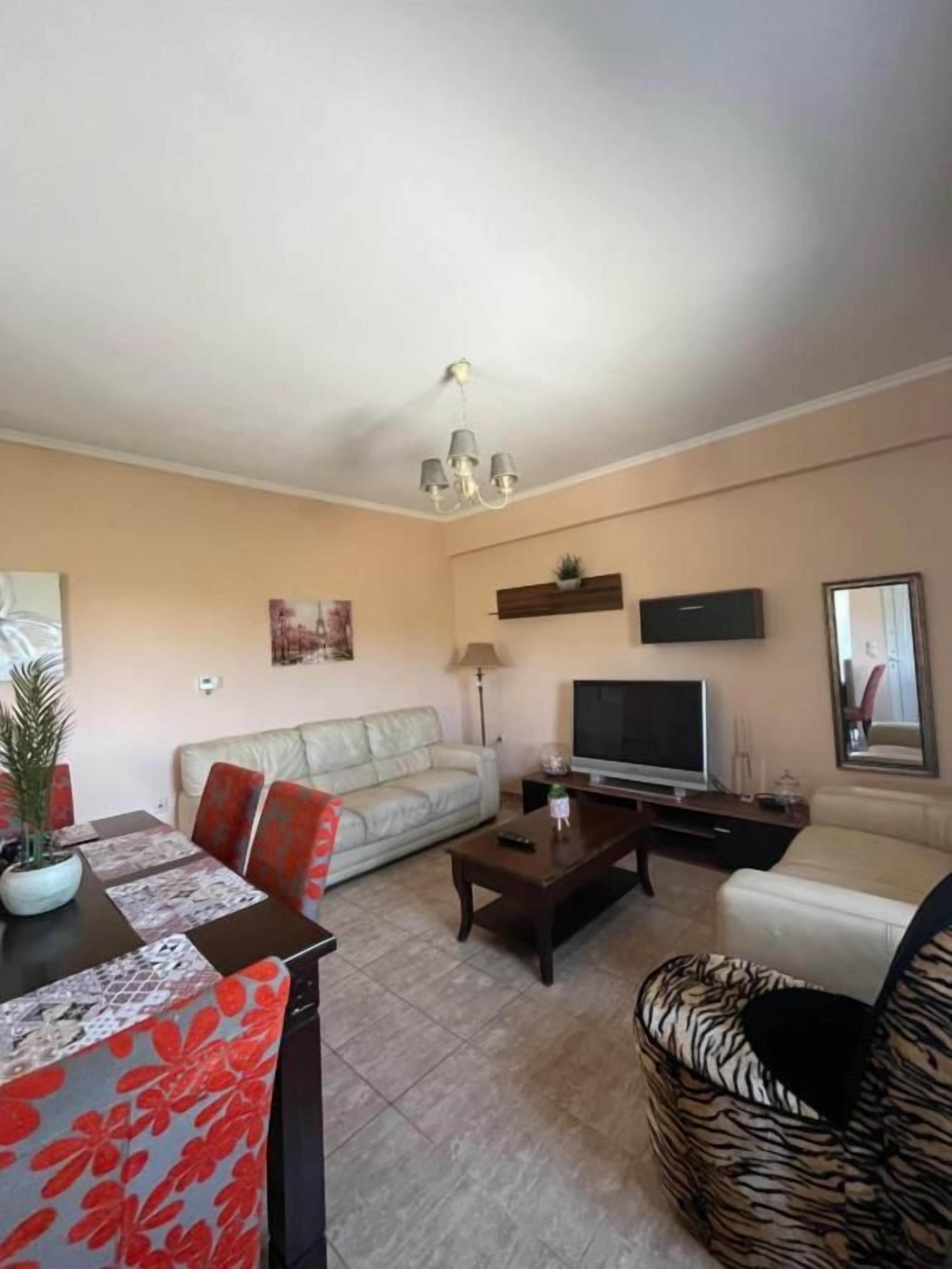 A living room with a sofa, a coffee table, a TV, and a dining table with chairs.