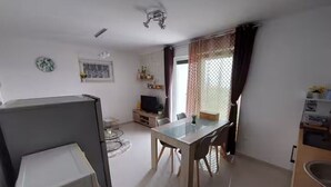 A compact living space with a dining area, kitchenette, and a small TV. - Villa Madlen - Sea View Apartment 1 (Opatija)