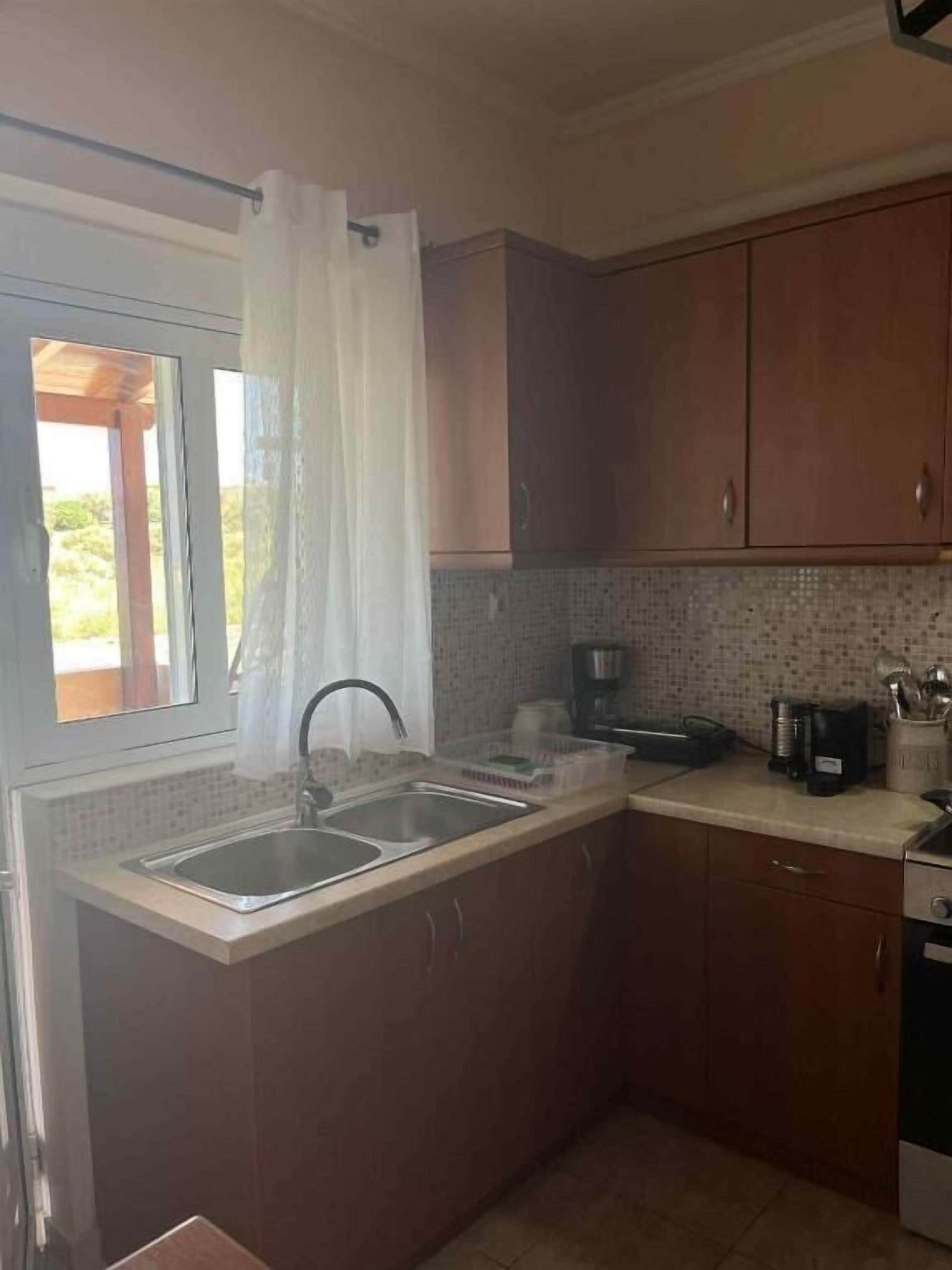 A kitchen with a sink, cabinets, and a coffee maker.