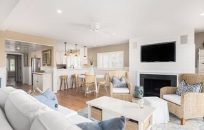 Ein modernes Wohnzimmer mit einer Couch, zwei Korbstühlen, einem Couchtisch und einem Kamin.