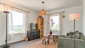 A modern living room with a sofa, a TV, a bookshelf, and a dining area with a table and chairs. - Villa 'Lo Ginest' with Mountain View, Wi-Fi, and Air Conditioning (Villedieu)