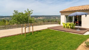 A patio with a table and chairs, a view of the countryside, and a building with a tiled roof. - Villa 'Lo Ginest' with Mountain View, Wi-Fi, and Air Conditioning (Villedieu)