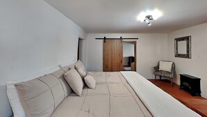Un dormitorio con una cama grande, una silla, un tocador y un armario.