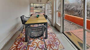 Un comedor con una mesa de madera, sillas negras y una alfombra estampada.