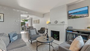 Ein Wohnzimmer mit Kamin, Fernseher und Essbereich mit Zugang nach draußen.